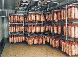 A large room filled with lots of meat hanging.