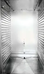 A white room with a metal door and a mirror.